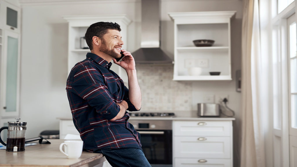 Shot of a young man using a smartphone in his kitchen at home
