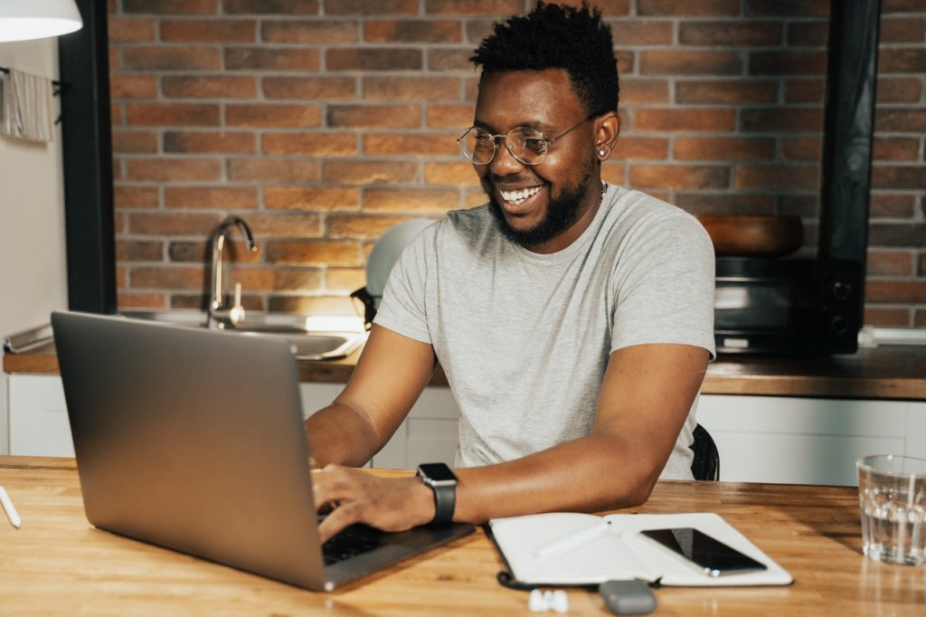 Black man smiling while working on lap top