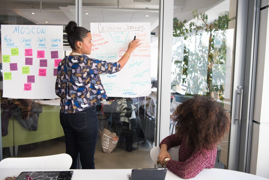 Woman discussing an outsource strategy plan, pointing on a whiteboard