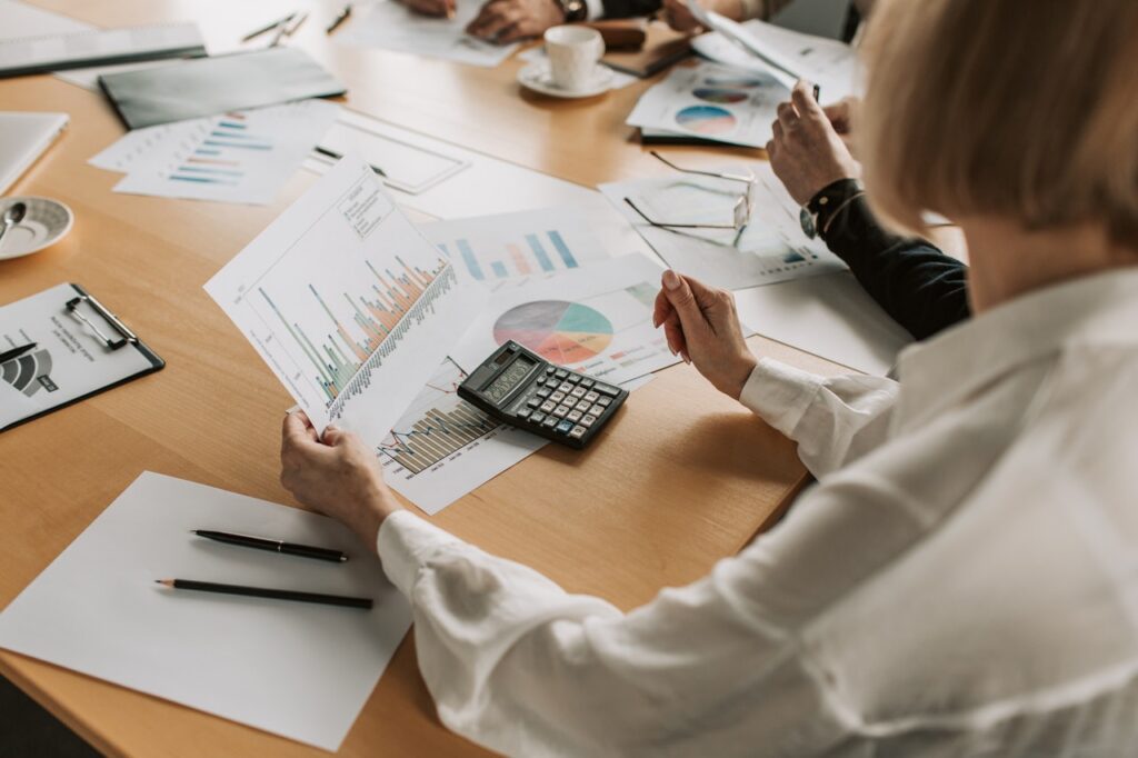 Group of professionals gathered around a table at work, actively discussing a paper with charts focused on customer experience