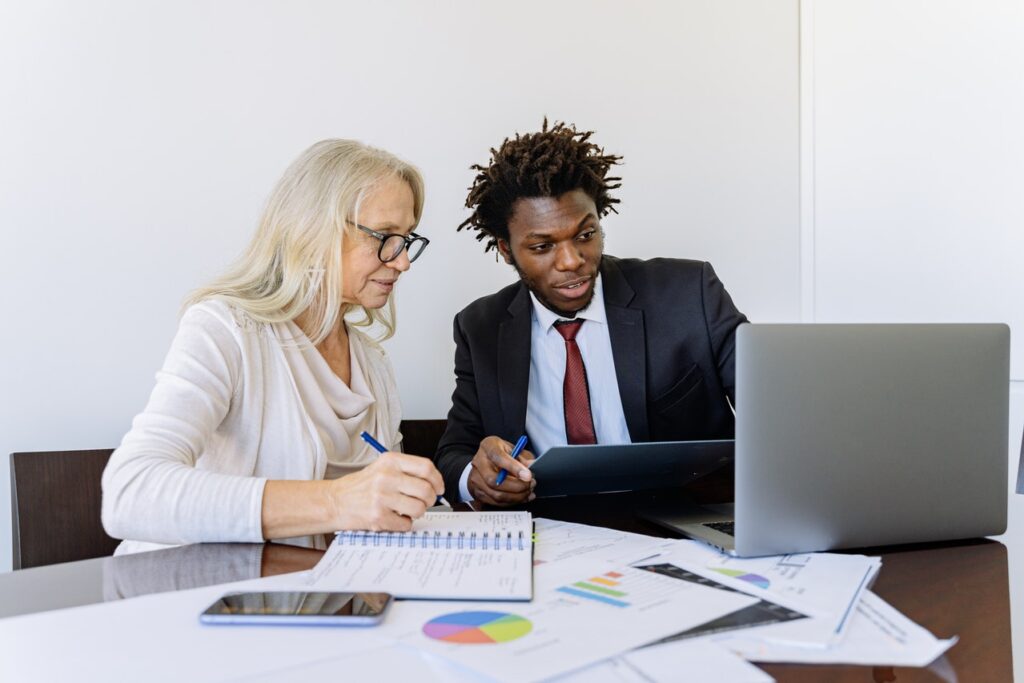 Two managers discussing Customer Experience strategies in a professional setting, in front of a lap top