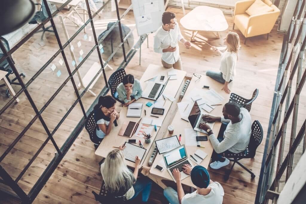 Top view of multiracial young creative people in modern office. Group of young business people are working together with laptop, tablet, smart phone, notebook. Successful hipster team in coworking. Freelancers.