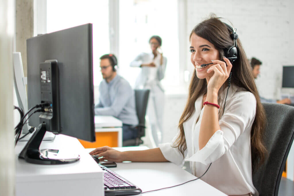 Happy smiling female customer service operator working on computer in office