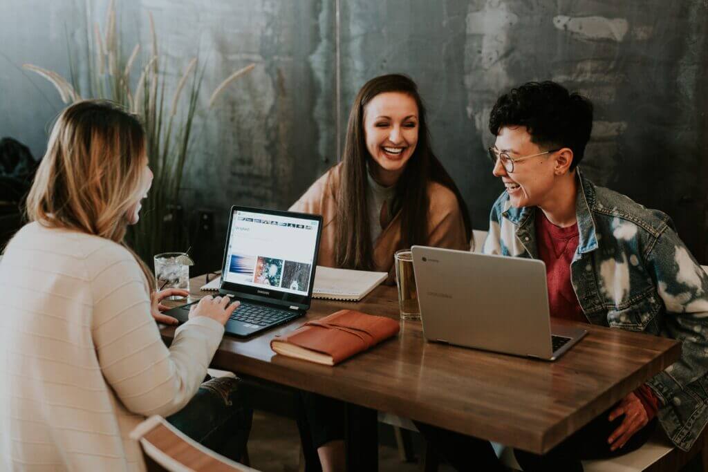 Three girls laughing while working in a coworking place