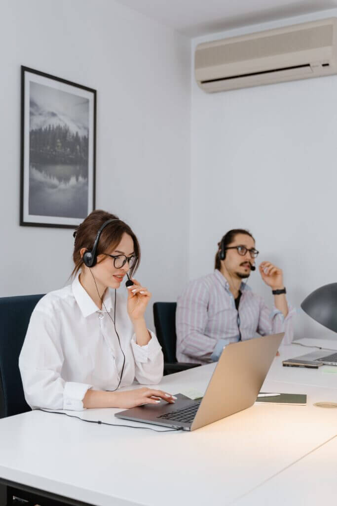 Two contact center employees speaking on their headsets.