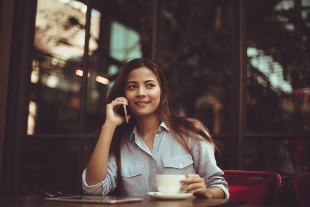 A young woman engaged in a phone conversation while sitting in a coffee shop.