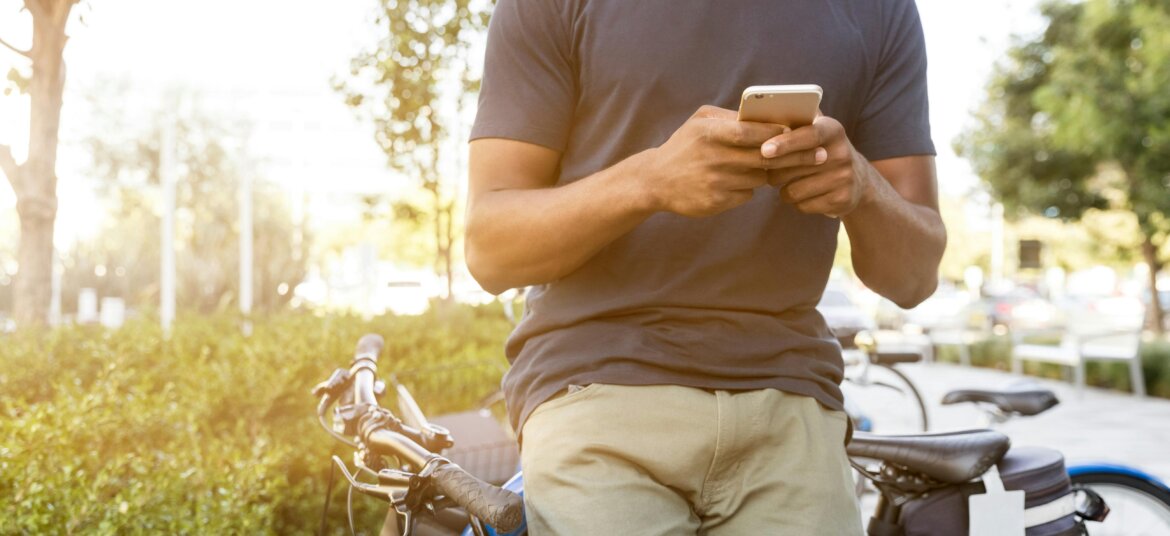 Person Leaning on Bike While Holding Smartphone